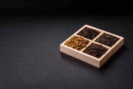 A wooden box with several types of dried tea, green, black, fruit, and chamomile. Dry tea in the box as a backdrop for your design.の写真素材