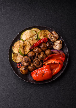 Grilled vegetables, bell peppers, mushrooms, and zucchini, a vegetarian healthy meal with sauce. Grilled vegetables on a plate as a food background for your design.の写真素材