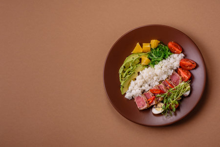 Seared tuna in a bowl with rice and vegetables.