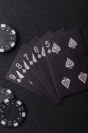 Playing card game poker in casino with chips, bets and risk. Cards and chips on black felt as...