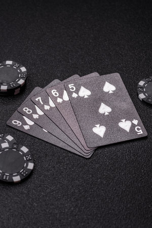 Playing card game poker in casino with chips, bets and risk. Cards and chips on black felt as...