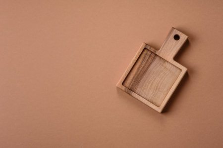 A wooden empty cutting board on a dark kitchen table. Wooden cutting board as a food background for...