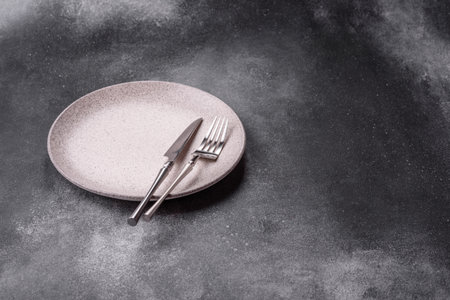 An empty round ceramic plate, knife, and fork as a dining table setting. An empty plate as a backdrop for your designの写真素材