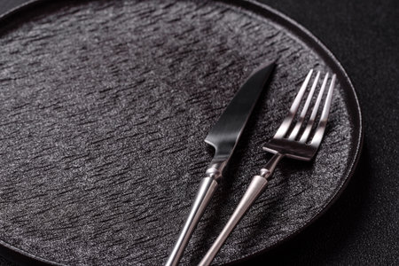 An empty round ceramic plate, knife, and fork as a dining table setting. An empty plate as a...