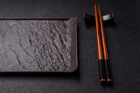 An empty ceramic square black plate with chopsticks for Asian food. An empty square plate as a food...