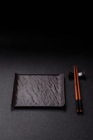 An empty ceramic square black plate with chopsticks for Asian food. An empty square plate as a food...