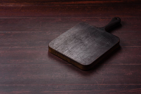A square wooden cutting board for home food preparation. A wooden cutting board serving as a food background for your design