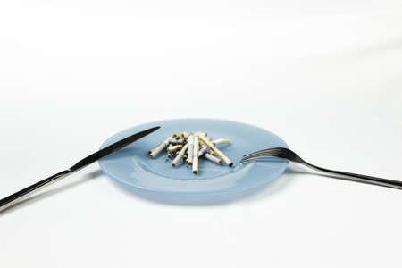Blue plate with cigarette butts and cutlery.の写真素材