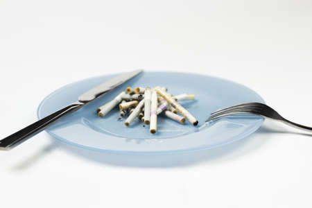 Blue plate with cigarette butts and cutlery.の写真素材