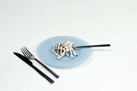 Blue plate with cigarette butts and cutlery.の写真素材