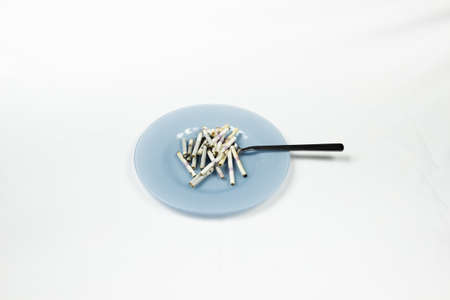 Blue plate with cigarette butts and cutlery.の写真素材