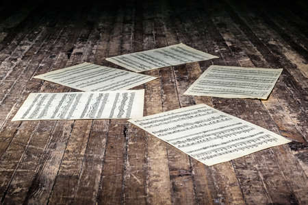 music sheets with notes of a musical work lie on the old floor in the darkの写真素材