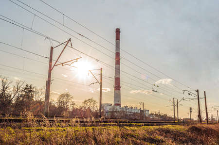 High pipe of thermal power station near the railway at sunsetの写真素材