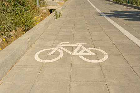 white bicycle silhouette sign, painted on path with bikeway