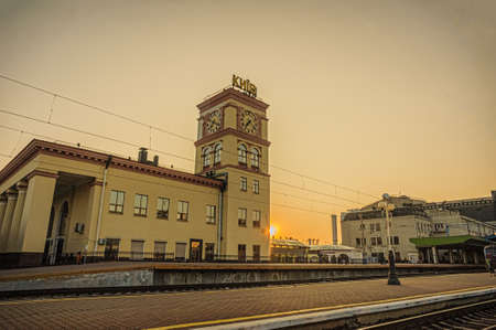 Suburban railway station building with clock tower and Kyiv-Pasazhyrskyi central railway station in...
