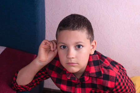 portrait of a european teenage boy with light brown hair wearing a red plaid shirt
