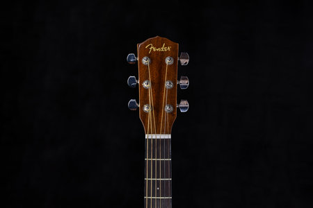 Fender acoustic guitar head with chrome tuning pegs and fretboard on isolated black background