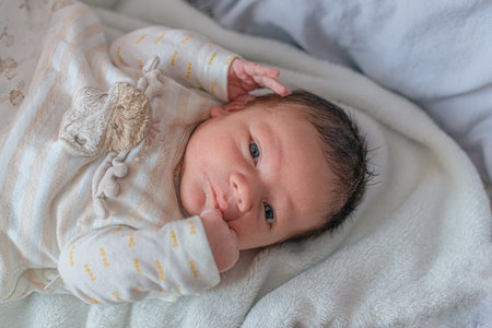 newborn baby lies on a blanket in his bed