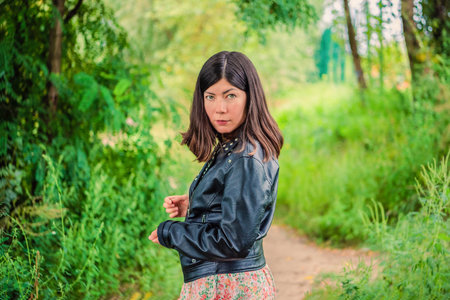 a young girl with black hair stands in the middle of the green forestの写真素材