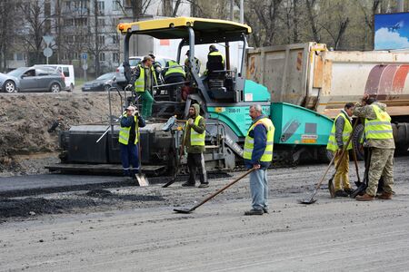 UKRAINE - APRIL 6, 2017: Workers operating asphalt paver machine and heavy machinery during road repairsのeditorial素材