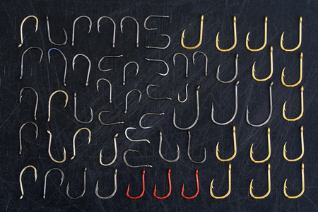 Fishing hooks isolated on a black background. Several metallic hooks lie randomly on the background.