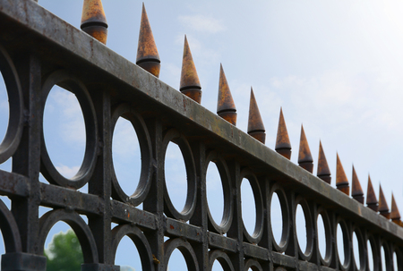 Beautiful wrought fence against blue sky. Image of a decorative cast iron fence. metal fence close up. Metal Forged Fence.の写真素材