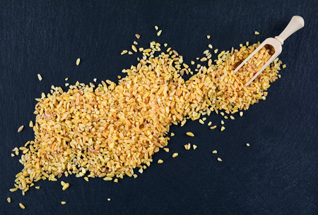 Dry bulgur wheat in the spoon on dark backgroundの写真素材