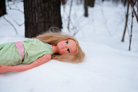 Children's doll in the snow. Lost toysの写真素材