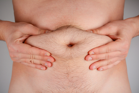 Overweight man squeeze fat on the waist. The problem of obesity.の写真素材