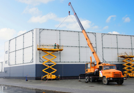 Workers install big billboard on the unfinished building supermarket. Construction crane.の写真素材