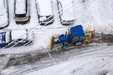 UKRAINE - DECEMBER 13, 2018: Tractor cleans the streets and parking from the fresh fallen snow. Heavy machinery outdoors cleaning road.のeditorial素材
