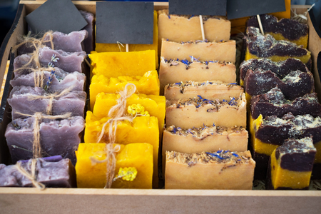 The multi-colored handmade soap is decorated with medicinal herbs It is laid out on the counter of the store and cut into pieces in close-up.の写真素材