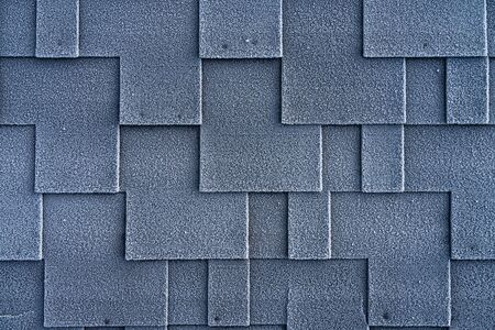 Close up view on asphalt roofing shingles covered with frost.