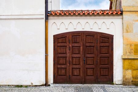 Old wooden gate antique tiles roof with white plaster wall.