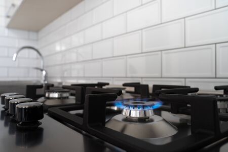 Blue flame from a gas stove burner. Stainless steel kitchen surface with cast-iron grill.の写真素材
