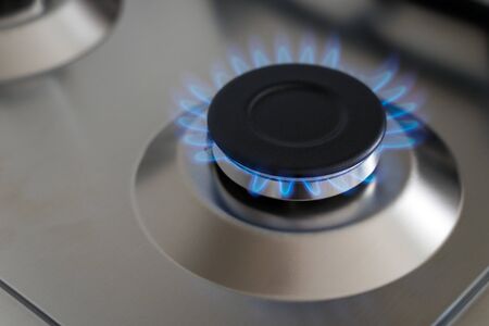 Closeup blue flame from a gas stove burner. Stainless steel kitchen surface.の写真素材