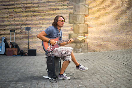 Italy - June 22, 2019: Street musician playing his guitar on the street in Rome.