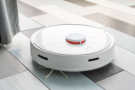 A robot vacuum cleaner helps in cleaning an apartment or house. Autonomous smart technologies.