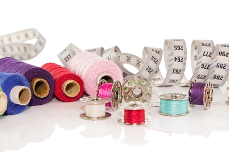 bright threads in basket, scissors and measuring tape isolated on white