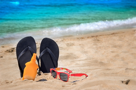 
Beach accessories ,sunglasses, sunscreen cream and flip flops on sand.の写真素材