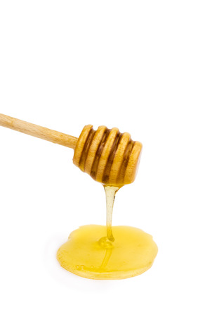 wooden dipper with honey isolated over whiteの写真素材