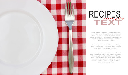 white plate and fork on red checked tablecloth with copy spaceの写真素材