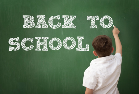 Schoolboy drawing BACK TO SCHOOL on blackboard, education conceptの写真素材