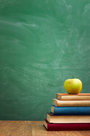 School books with apple on desk over green  school board backgroundの写真素材