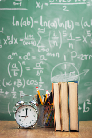 School books with supplies over green tableの写真素材