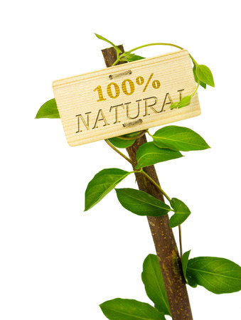 100 percent natural sign message on a wooden panel and green plant - image is isolated on a white backgroundの写真素材