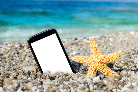 Starfish and smartphone in the sand on beach, summer holidayの写真素材
