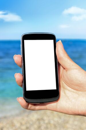 Hand holding mobile phone at the beach, travel and summertime holidaysの写真素材