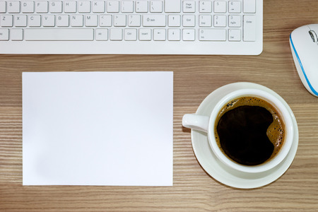 Office table with empty white paper and cup of coffeeの写真素材