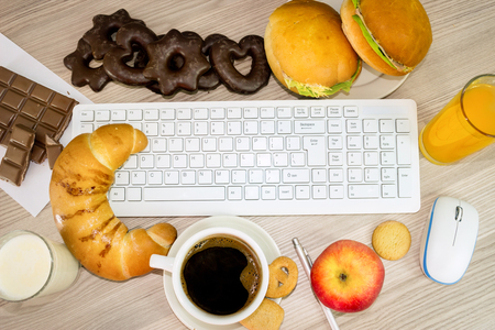 lunchtime in office, keyboard covered with food that we eat during workの写真素材